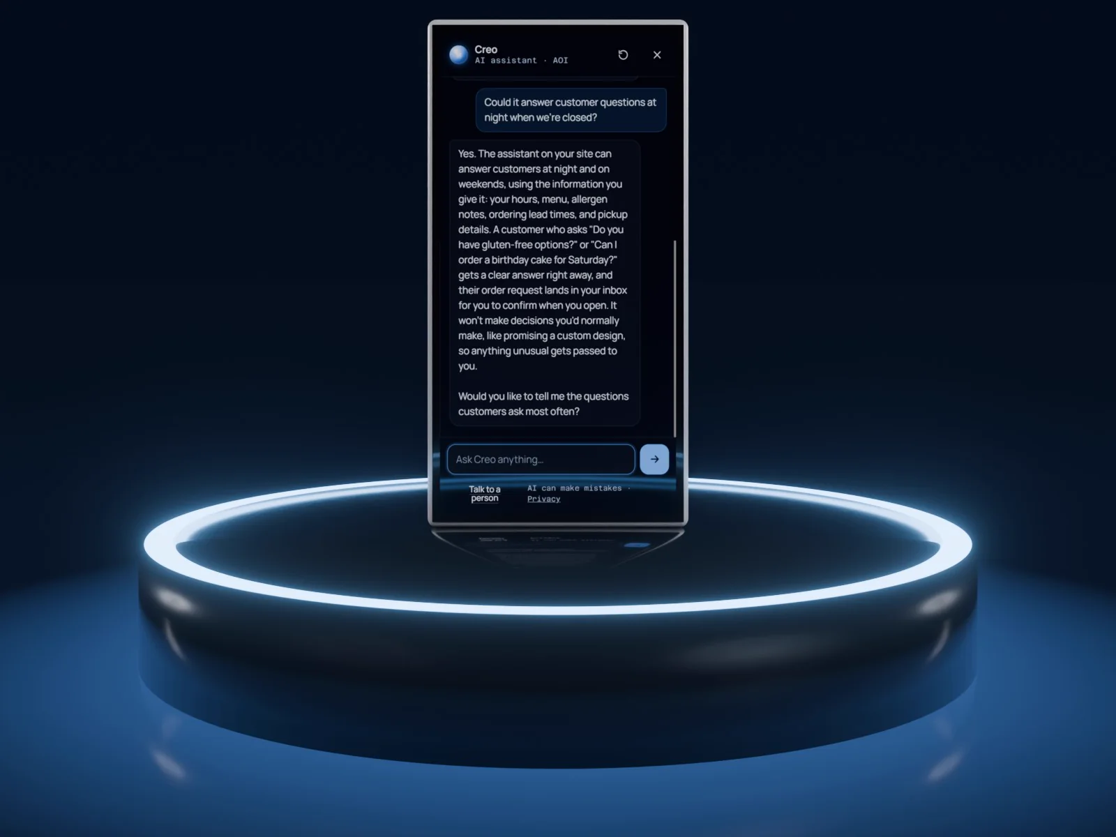 A silver phone standing on a glowing display stand, showing a real conversation with Creo: a customer asks if we can build a bakery website that takes orders and whether it can answer questions at night, and Creo explains.